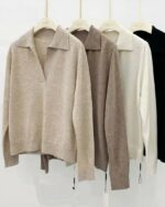 Photo de quatre pulls polo en laine sur cintres : un noir, un blanc, un beige et un marron le tout sur un fond gris clair