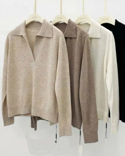 Photo de quatre pulls polo en laine sur cintres : un noir, un blanc, un beige et un marron le tout sur un fond gris clair