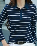 Polo à manches longues rayé blanc et bleu porté par une femme avec un pantalon blanc