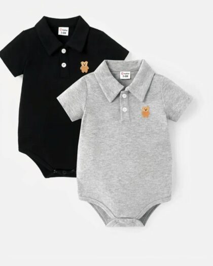 On voit deux polos body pour bébé. Un noir et un gris, il sont un écusson en forme de tête d'ourson brodé sur la poitrine.