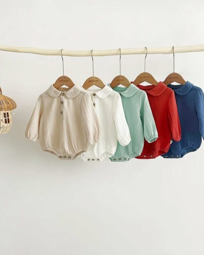 Sur fond beige, on voit cing bodys polos sur une tringle.