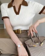 Polo beige et marron manches courtes . Porté une femme en pantalon beige et portant un sac à main
