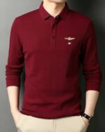 Homme portant un polo à manches longues rouge sur fond gris.