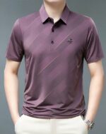 Homme portant un polo violet à manches courtes sur fond gris.