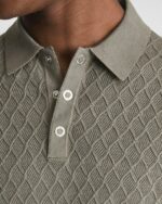 Homme portant un polo en tricot beige, on voit seulement le col.