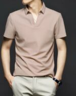 Homme portant un polo beige sans bouton sur fond noir.