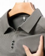 Polo gris tissu rayé sur un ceintre.