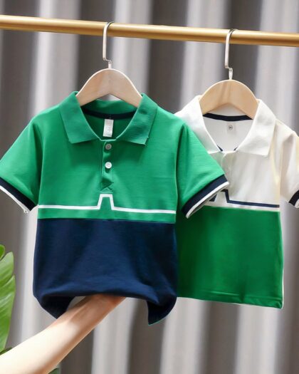 On voit deux polos vert et blanc pour bébé garçon suspendus à une tringle.