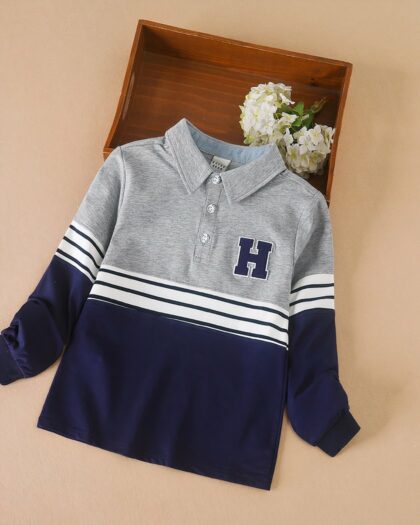 Sur fond beige, on voit un polo gris et bleu, style américaon, pour garçon.