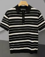 Polo marinière avec des rayures fines et plus larges, noir et blanc, sur un cintre, sur fond gris.