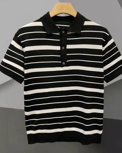 Polo marinière avec des rayures fines et plus larges, noir et blanc, sur un cintre, sur fond gris.