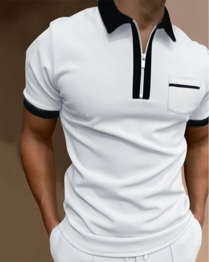 Polo zippé blanc au détails noir avec une poche poitrine porté par un homme avec un pantalon blanc, les mains dans les poches.