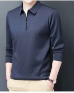Polo zippé manches longues bleu marine porté par un homme avec un pantalon beige les mains dans les poches.