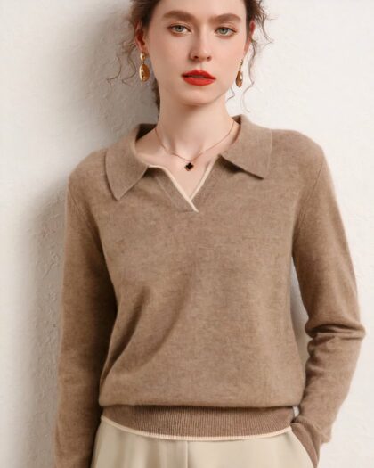 Photo d'une femme adossée à un mur beige portant un pull polo marron clair en cachemire sans bouton et la main gauche dans la poche d'un pantalon beige