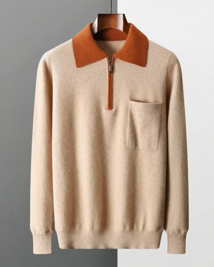 Photo d'un pull polo zippé bicolore beige et marron avec poche poitrine présenté sur cintre en bois marron foncé le tout sur un fond gris clair à droite et gris foncé à gauche