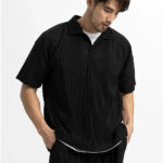 Homme portant un polo noir sans bouton sur fond blanc.