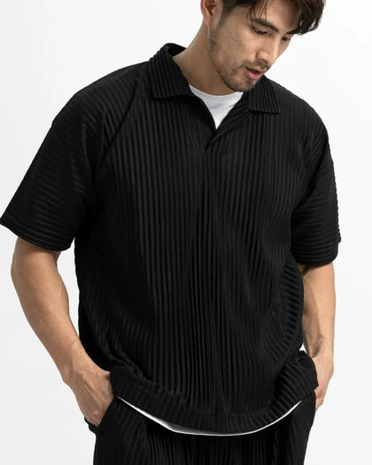 Homme portant un polo noir sans bouton sur fond blanc.