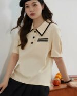 Photo d'une femme portant un polo vintage beige appuyé sur un meuble en bois/