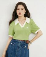 Femme portant un polo vert sur un fond gris.