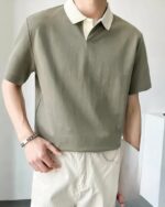Homme portant un polo vert et un pantalon beige.