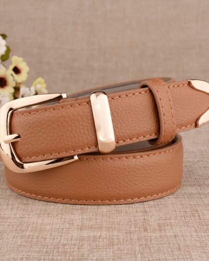 Ceinture fine pour femme de couleur camel avec une boucle doré, enroulée sur elle même avec des fleurs en arrière plan.
