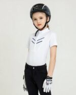 Petite fille en tenue d'équitation - polo blanc à manches courtes, pantalon bleu marine et une bombe sur la tête