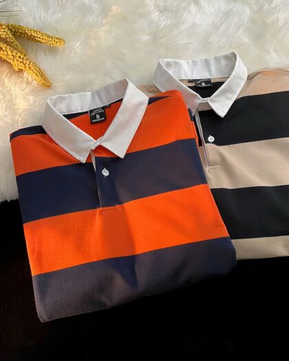 On voit deux polos de rugby rayés : un rouge et bleu et un noir et beige.