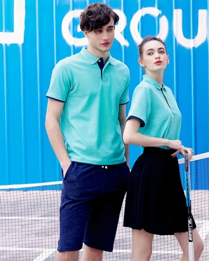 On voit un homme et une femme portant un polo bleu sur un court de tennis.