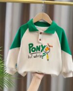 O, voit un polo manches longues blanc et vert avec une inscription de dessin animé sur le torse