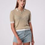 Femme qui porte un polo beige à manches courtes et un col zippé, en mailles côtelées