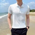 Polo blanc élégant porté par un homme à la plage