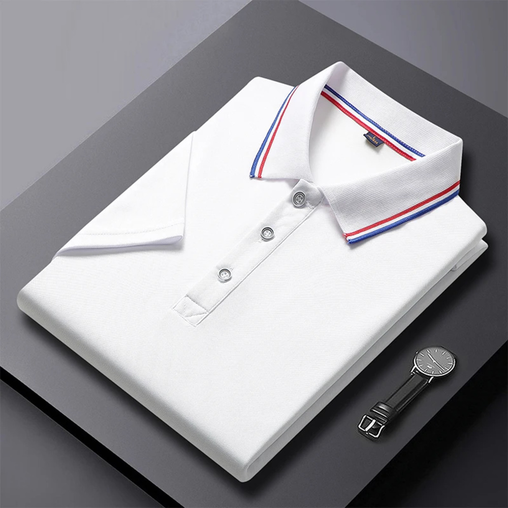 IMG_08_30_polo_chic_col_bleu_blanc_rouge_homme_1.jpg Un polo chic col bleu blanc rouge pour homme blanc plié, avec col et manches bordés de bleu et rouge, posé sur un fond gris avec une montre à côté.